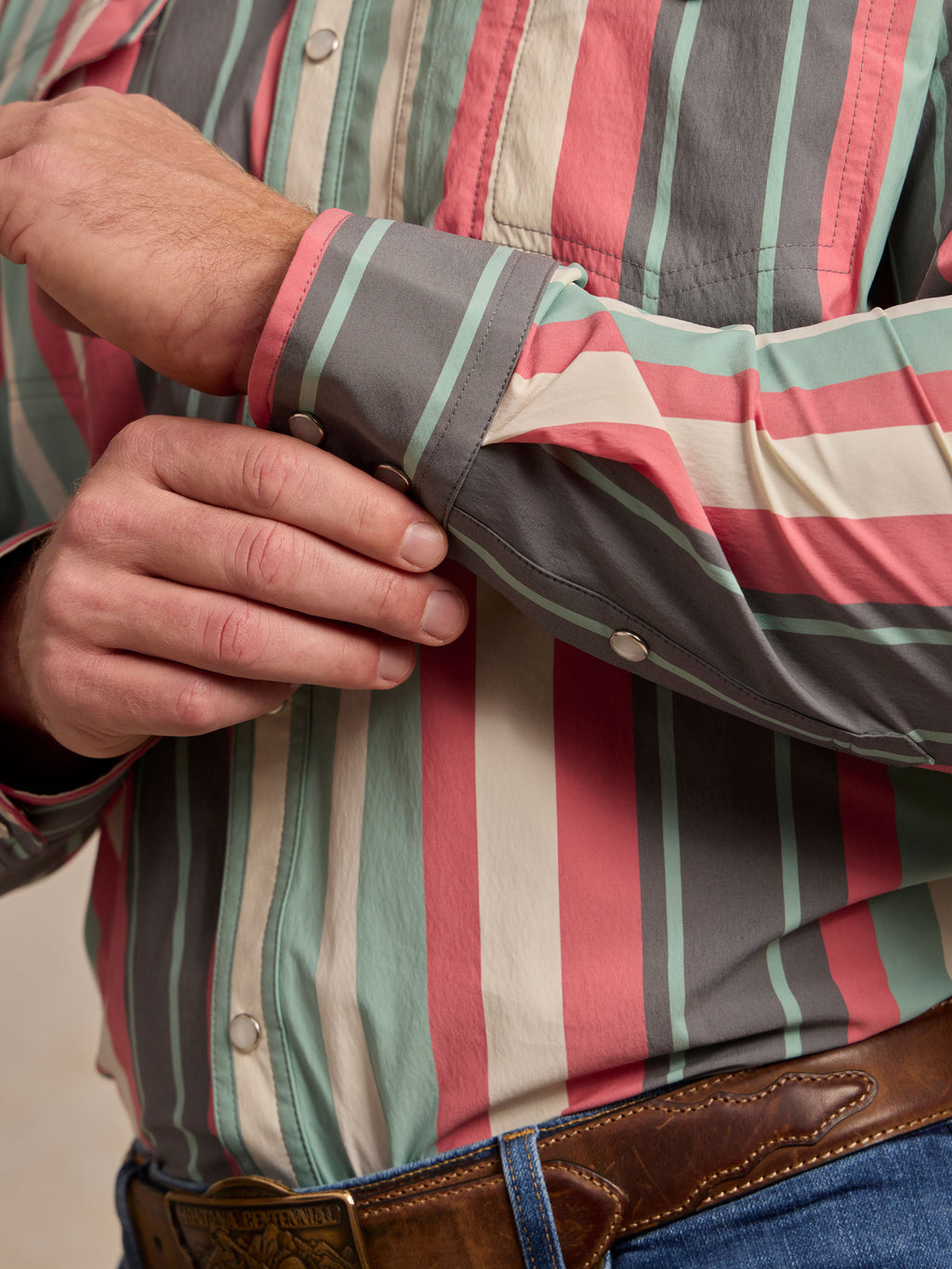 Western snap shirt sleeve detail with snap cuffs and teal-pink-white stripes.