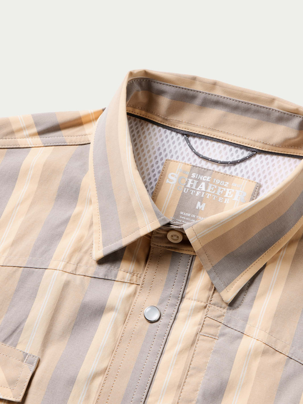 Inside collar close-up of striped snap shirt with metal snap and size label