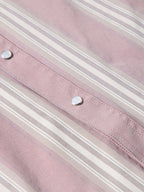 Pink striped shirt fabric close-up with rows of stitching and metal buttons