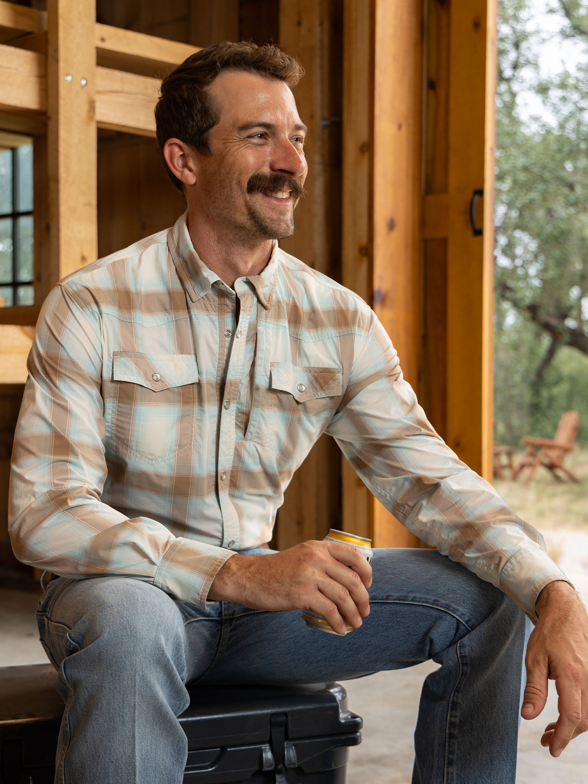 Man wearing a Western snap shirt in light blue and tan plaid with snap front buttons