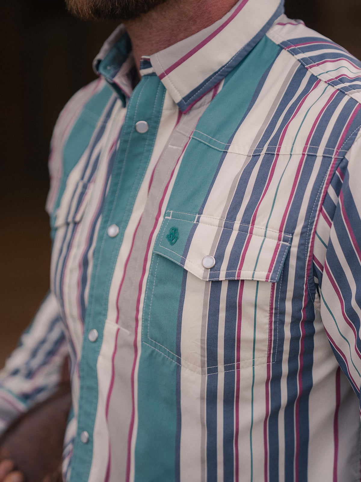 Women’s western snap shirt with vertical stripes, teal yoke panel, and button pockets
