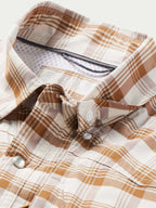 Tan-and-white plaid western snap shirt front with two chest pockets and metal snaps.