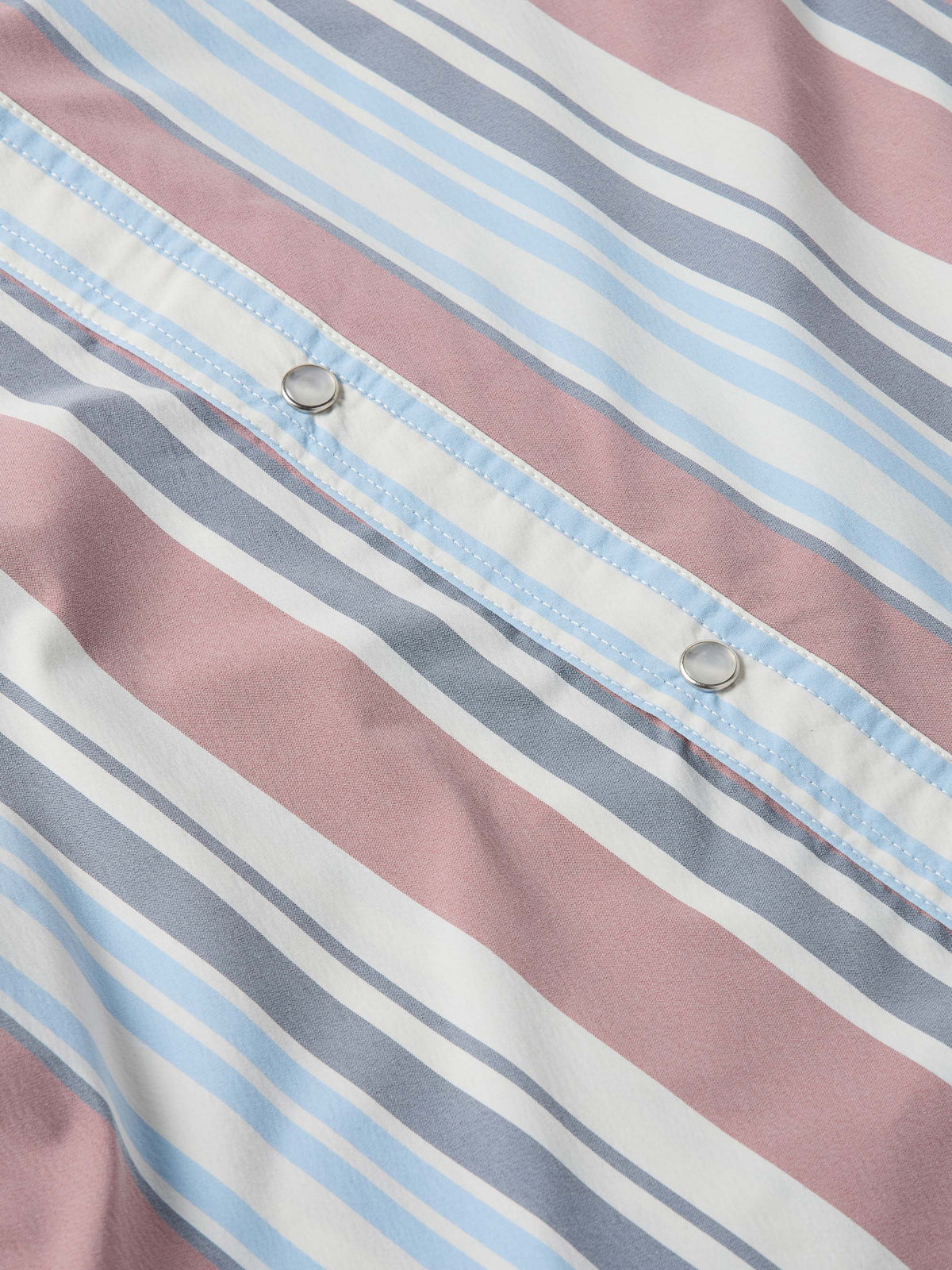Close-up of striped western snap shirt placket with metal snaps, pink and blue