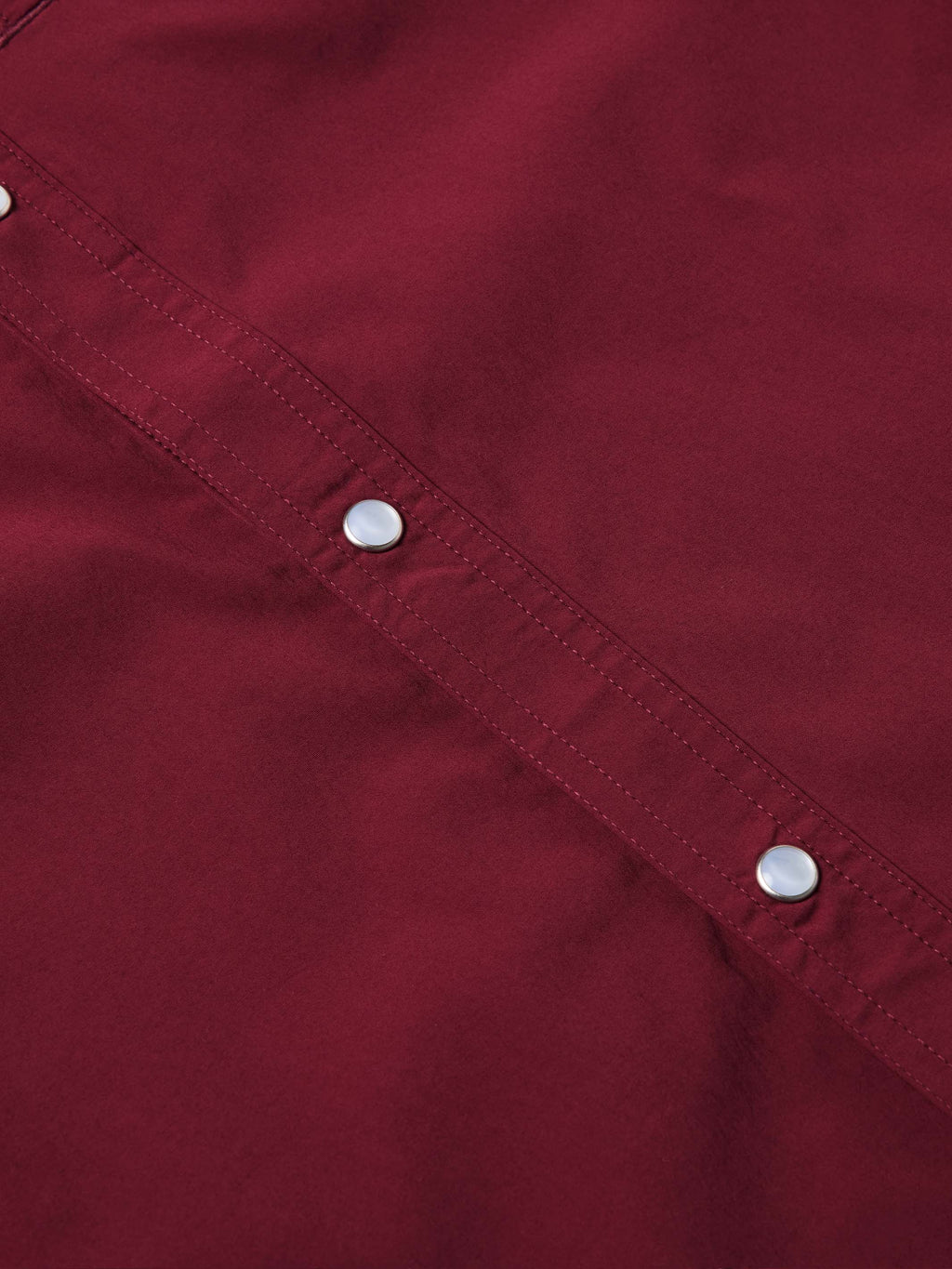 Maroon long-sleeve shirt seam detail with snap buttons along the chest