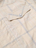 Snap shirt chest pocket detail, cream with blue plaid, snap flap and embroidered emblem.