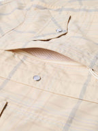 Western guide snap shirt fabric detail, cream with blue plaid, snap placket and buttons.