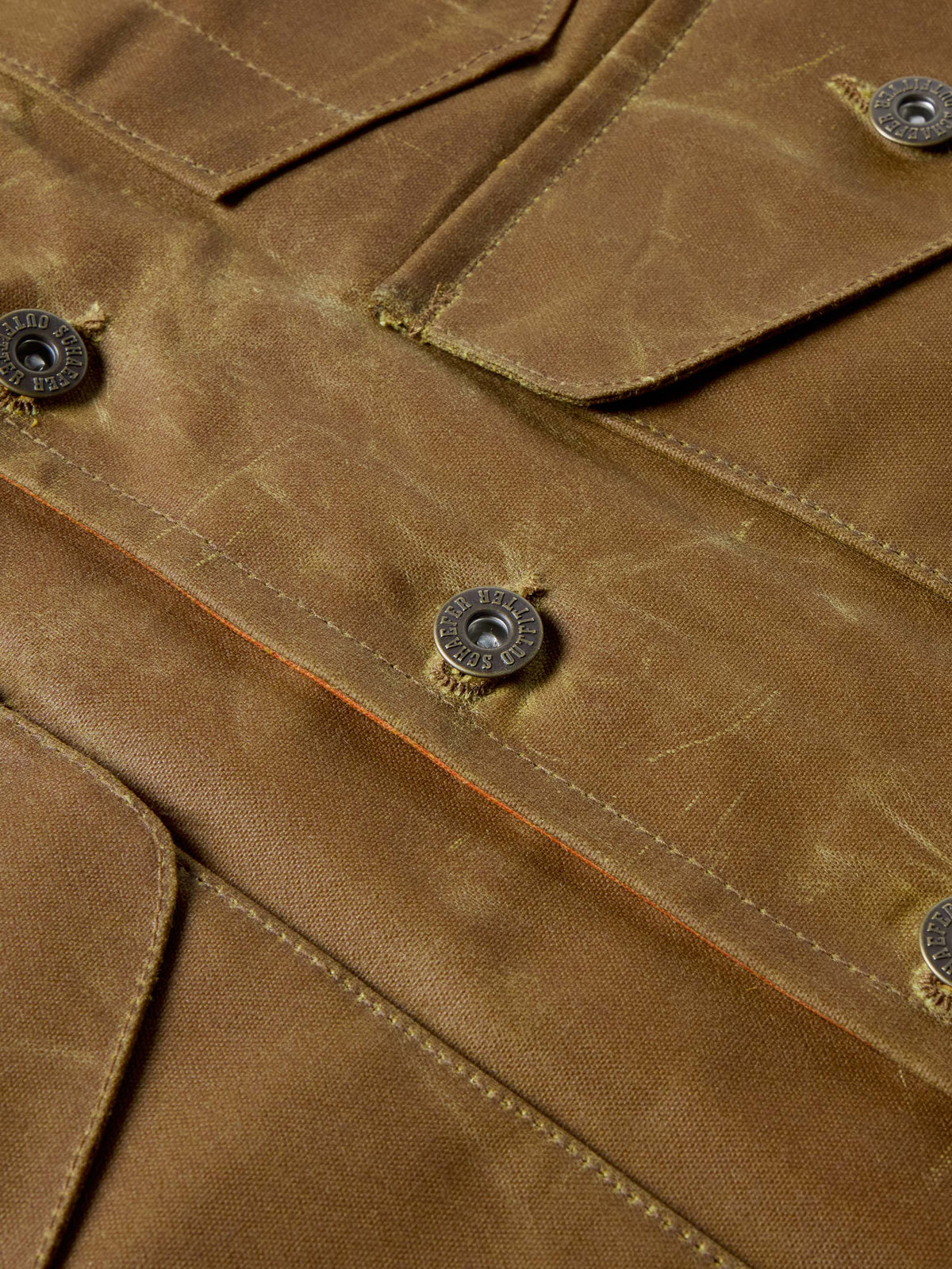 RangeWax® Mesquite vest close-up of brown fabric seams and metal snap buttons.