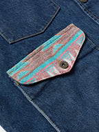 Close-up of blue denim pocket flap with round button and colorful textile trim