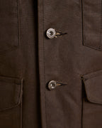 Close-up of dark brown vest with metal snap buttons and stitched placket