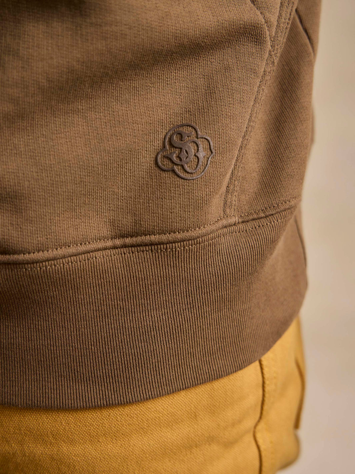 Olive cotton hoodie with embossed clover logo on sleeve cuff