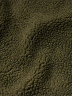 Close-up of olive sherpa fleece texture with dense, curly pile.