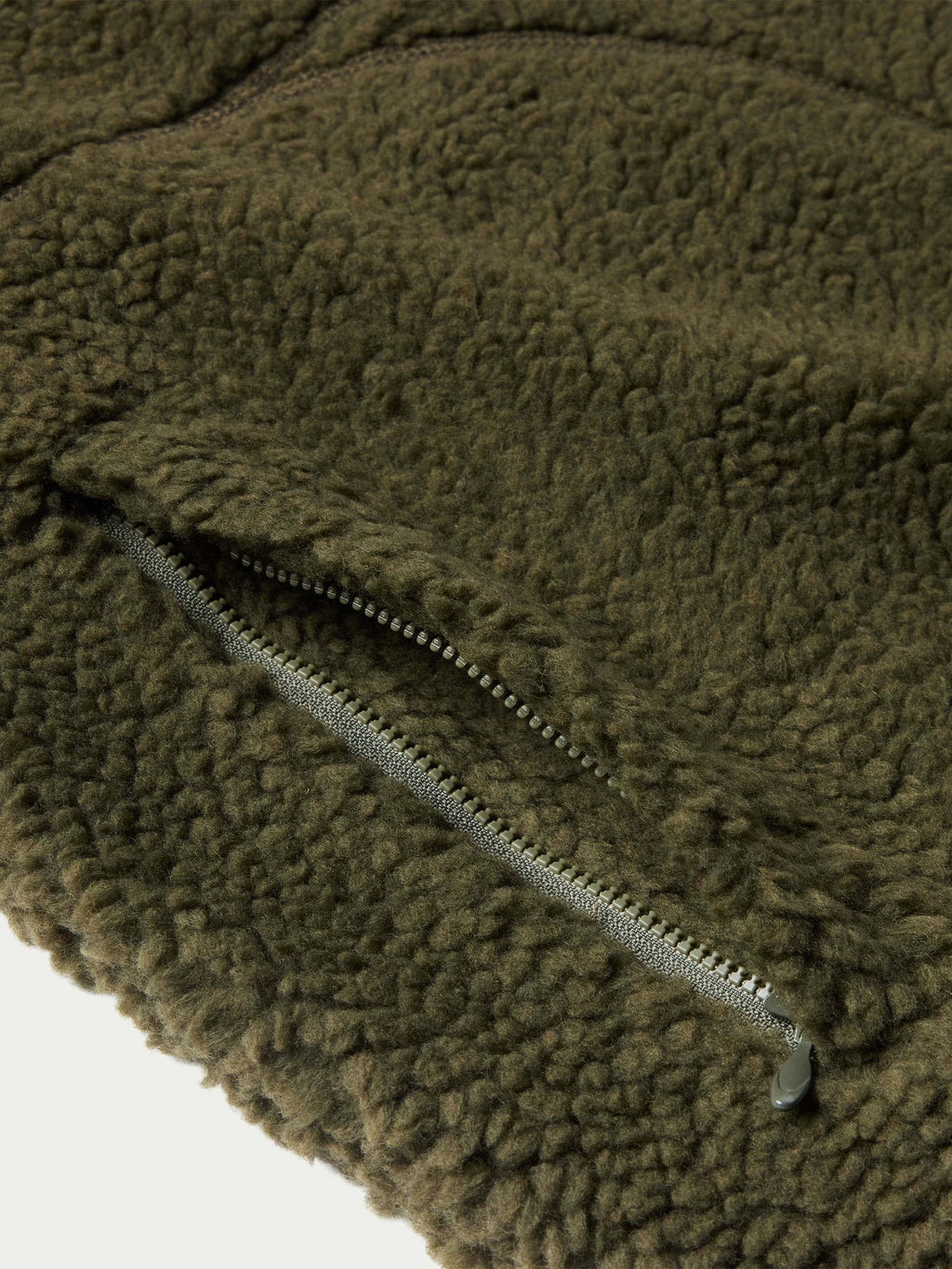 Olive fleece jacket close-up showing front zipper and textured fabric surface.
