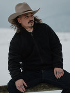 Washed black full-zip fleece jacket worn by man, stand collar and zip front.