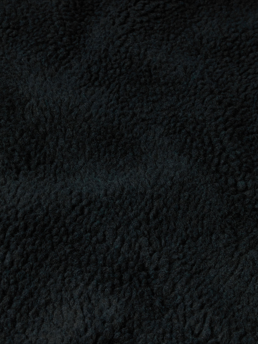Black fleece fabric close-up with dense textured pile.