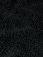 Black fleece fabric close-up with dense textured pile.