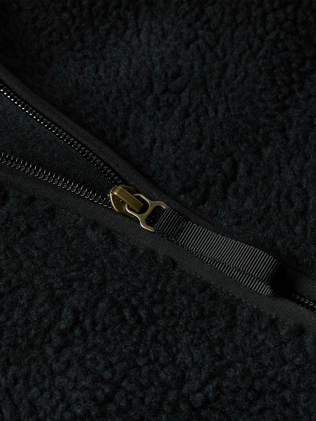 Black fleece jacket zipper with metal pull and branded tab.