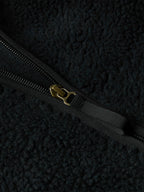 Black fleece jacket zipper with metal pull and branded tab.