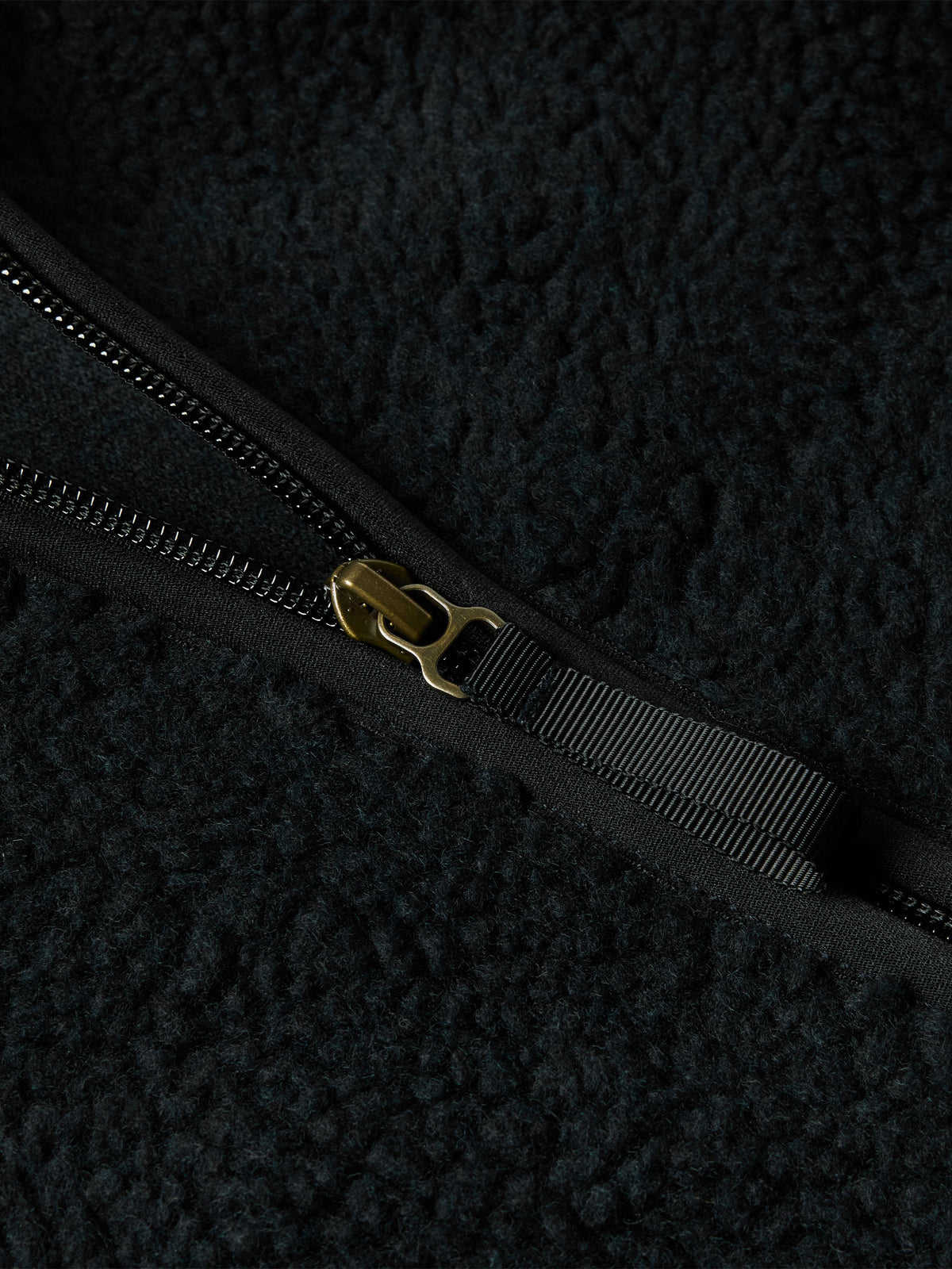 Black fleece jacket zipper with metal pull and branded tab.