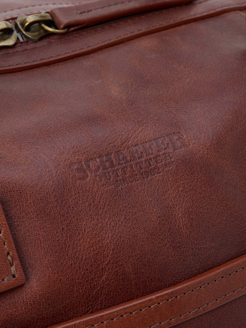 Russet leather duffel exterior with stitched trim and embossed branding.