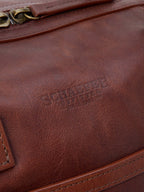 Russet leather duffel exterior with stitched trim and embossed branding.