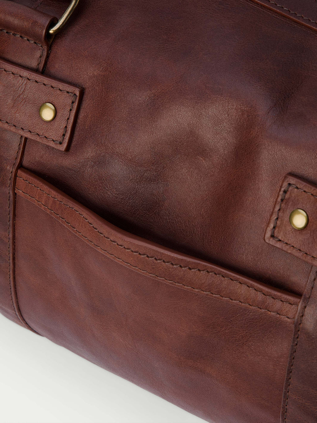 Russet leather duffel side pocket with brass snap button and contrast stitching.