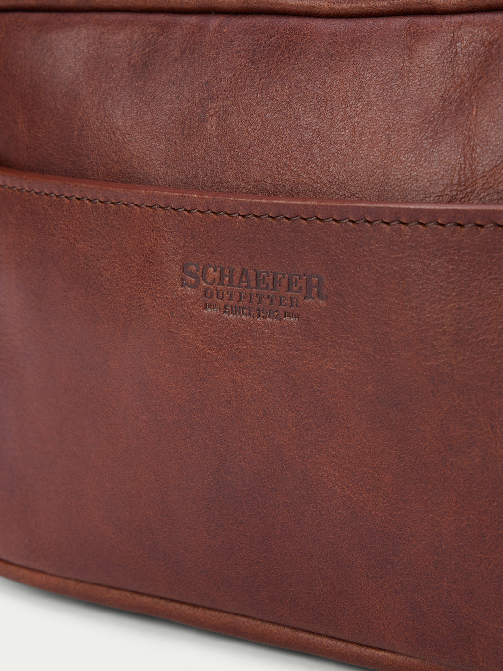 Russet leather dopp kit with embossed logo on front and zip closure