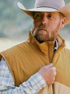 Tan quilted vest on model with hood and front zipper