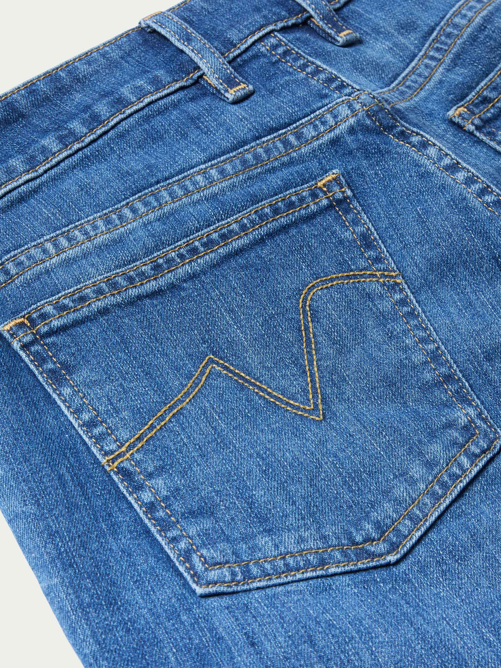 Medium-wash jeans close-up: stitched front pocket with decorative seaming and rivets.