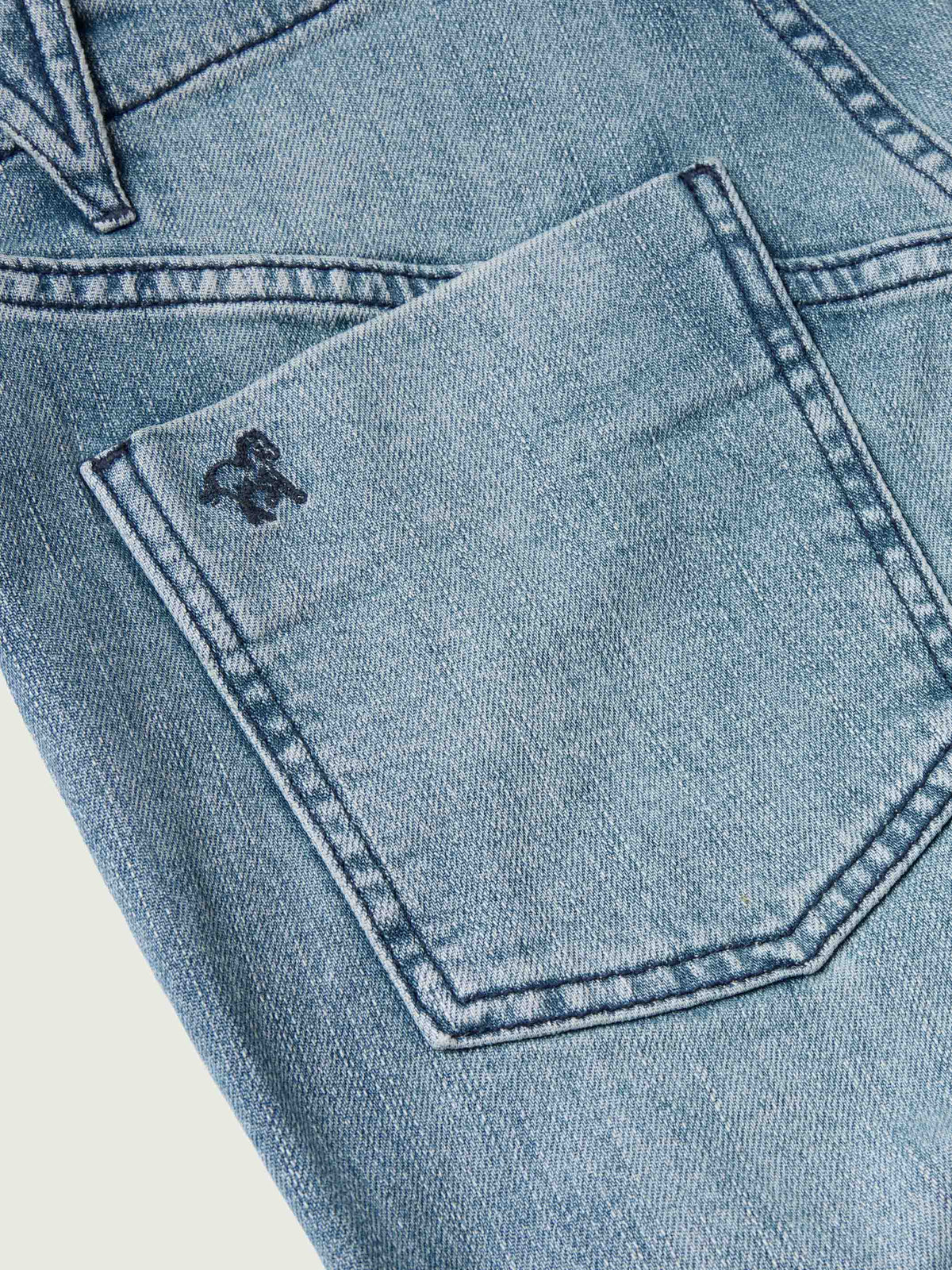 Medium wash denim jeans showing back pocket stitching detail