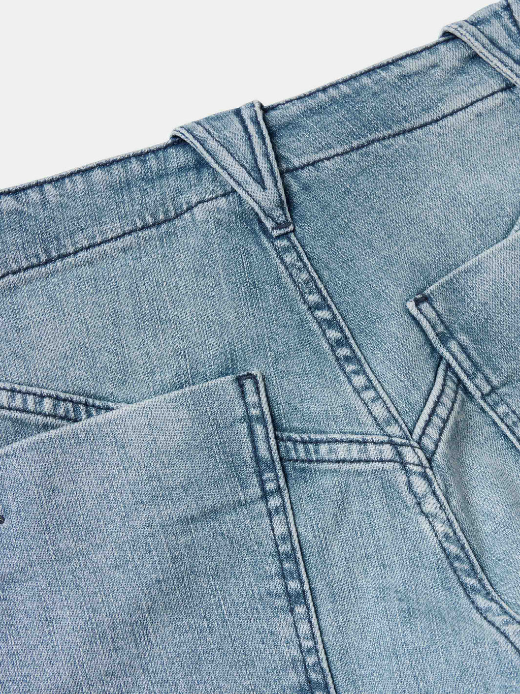Medium wash denim jeans close-up of waistband and front seam stitching