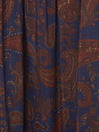 Paisley pattern fabric close-up on dark blue skirt with rust-orange swirls.