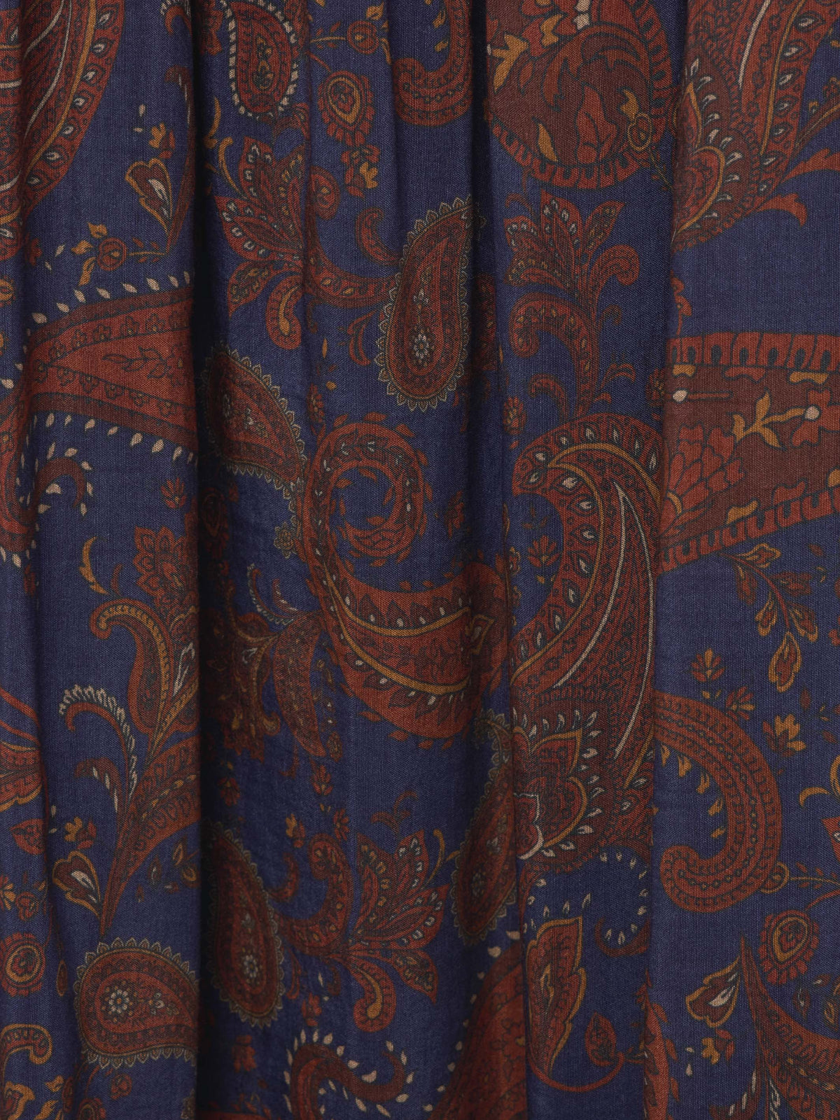 Paisley pattern fabric close-up on dark blue skirt with rust-orange swirls.