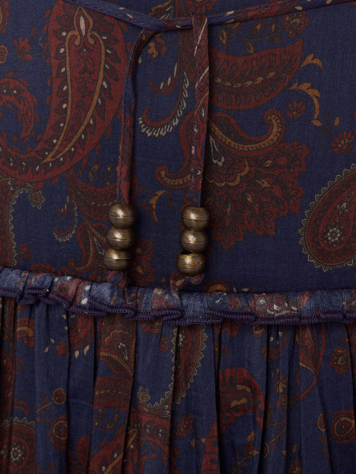 Elastic waistband on dark blue paisley skirt with rust tones and bead drawstring details.