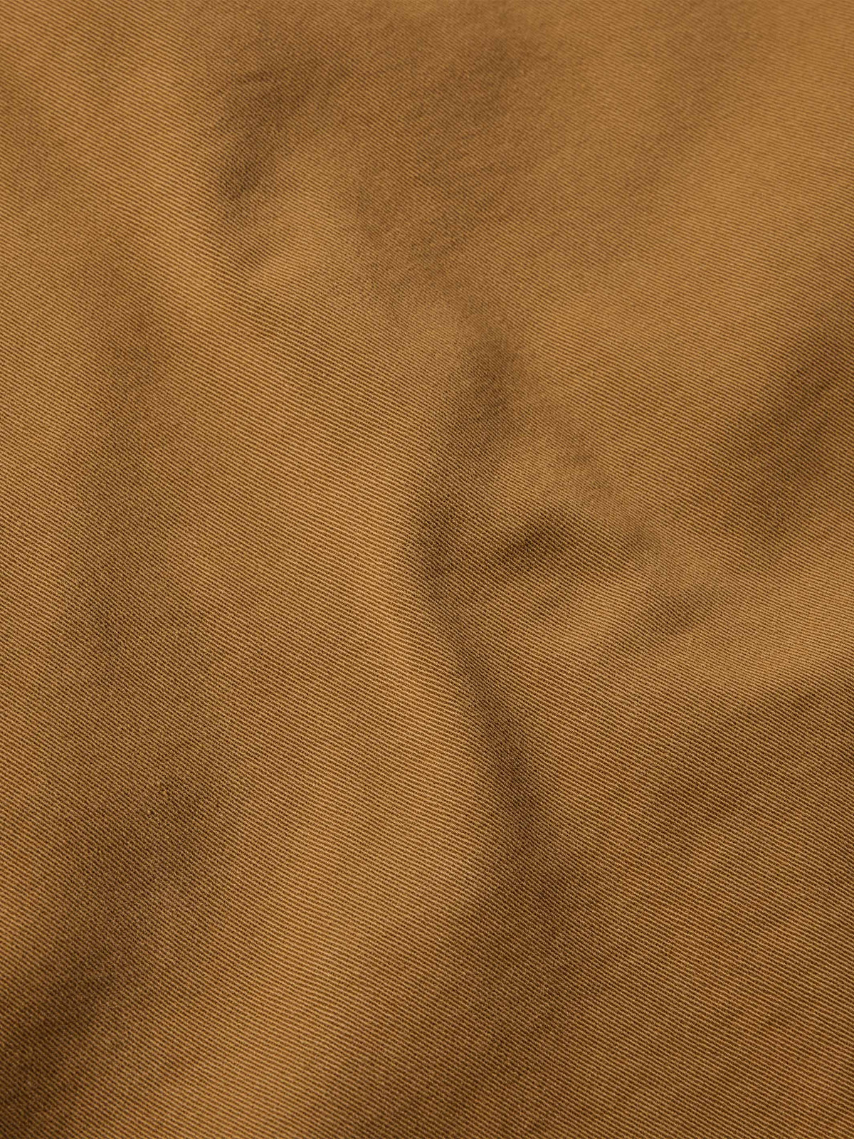 Close-up of fawn denim fabric texture with fine twill weave.