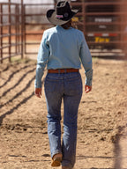 Turquoise women's snap-front denim shirt on model from behind with yoke seam