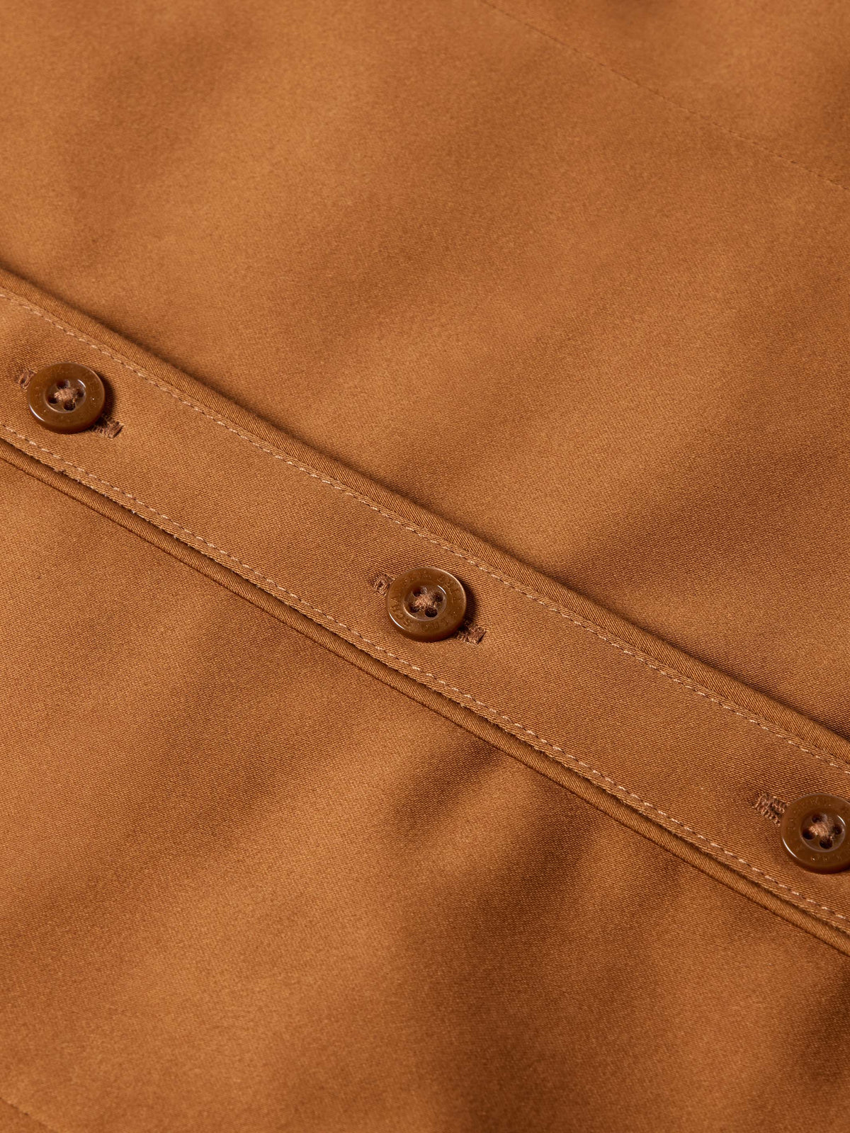 Dark caramel button placket detail with round buttons and stitched seams