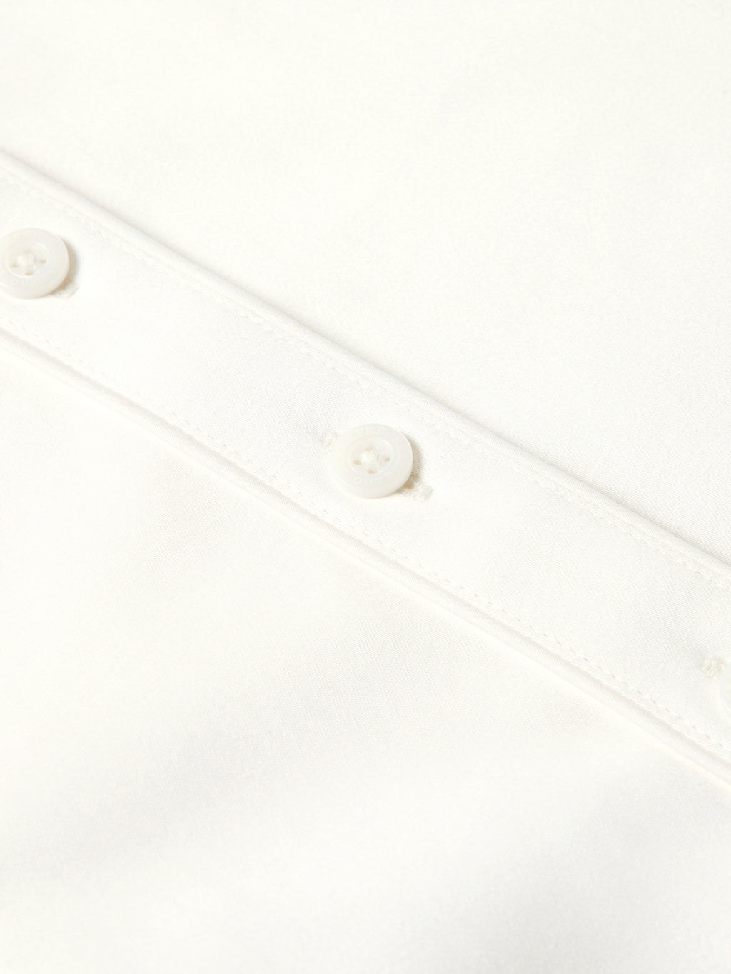 Close-up of white shirt button placket with round white buttons and stitched seams