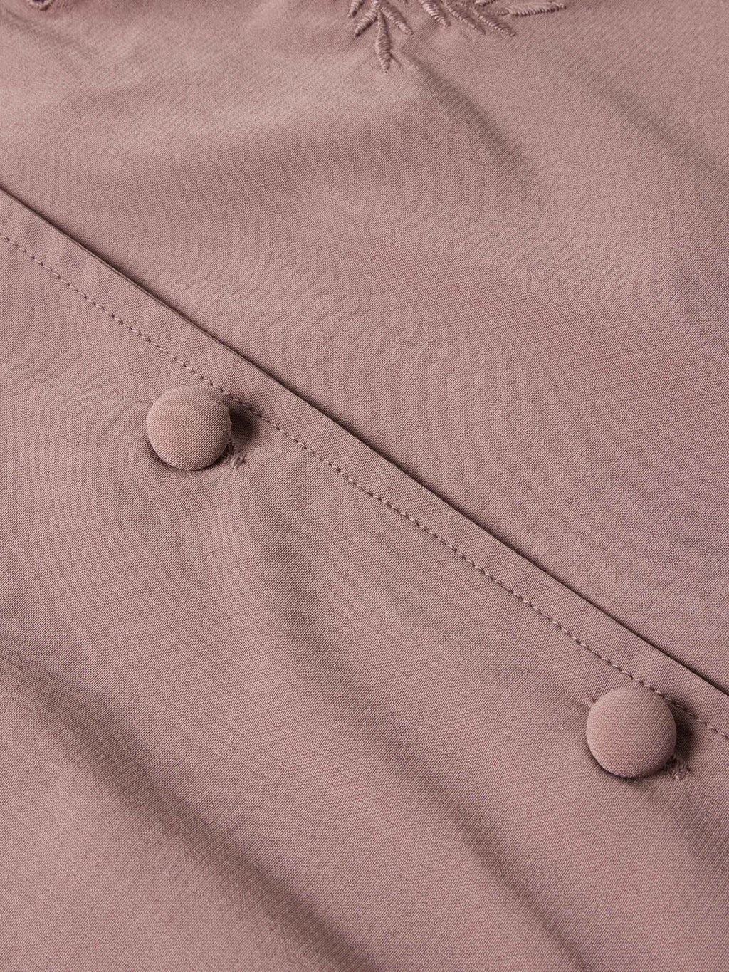 Washed plum blouse button placket close-up with round buttons and stitched seams