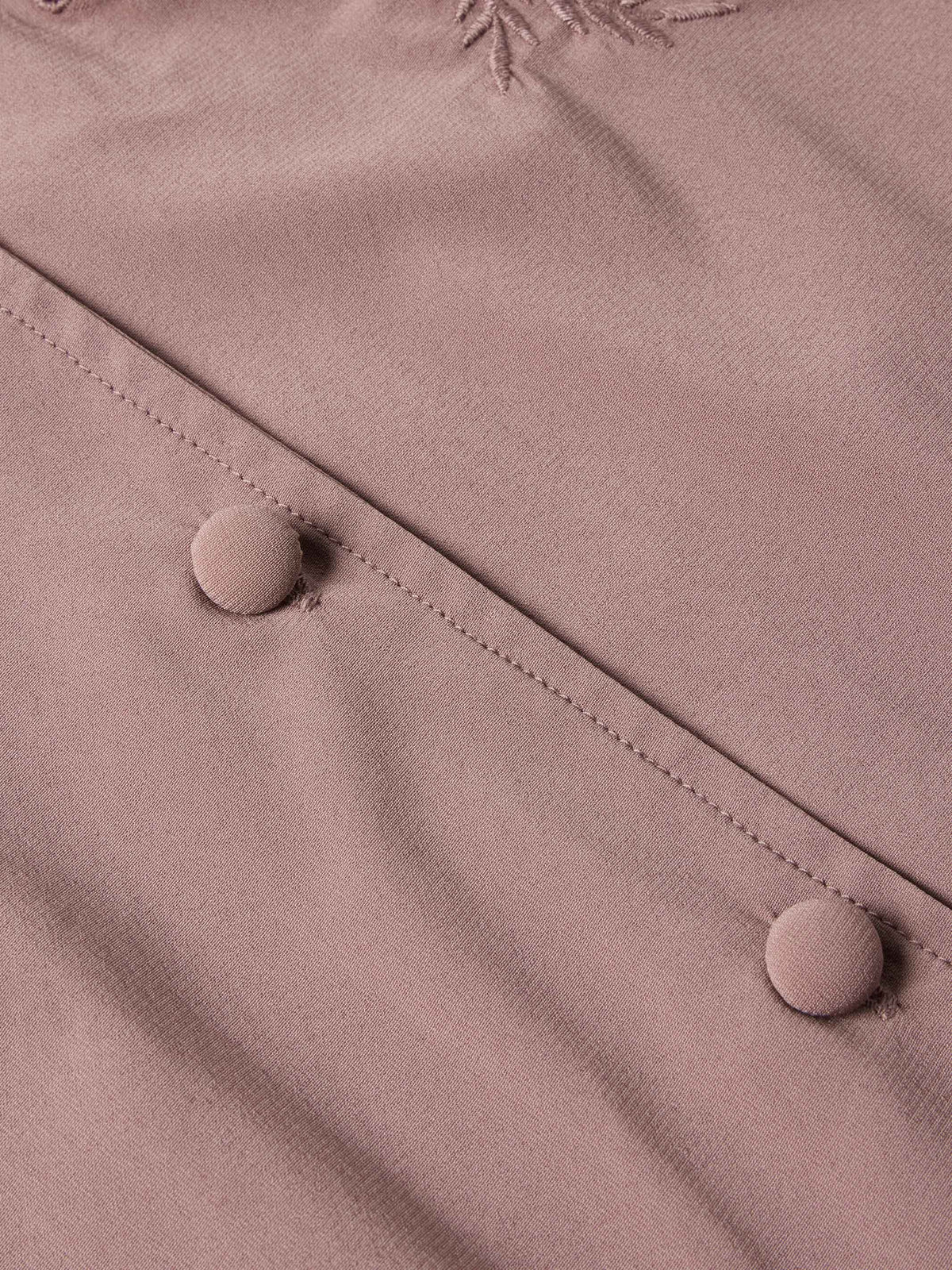 Washed plum blouse button placket close-up with round buttons and stitched seams