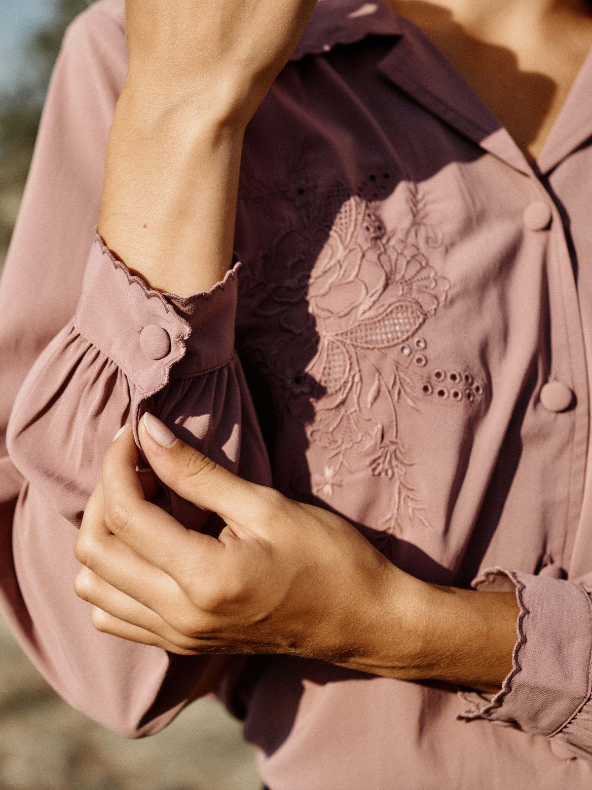 Close-up of washed plum blouse sleeve and embroidered yoke with scalloped ruffle trim