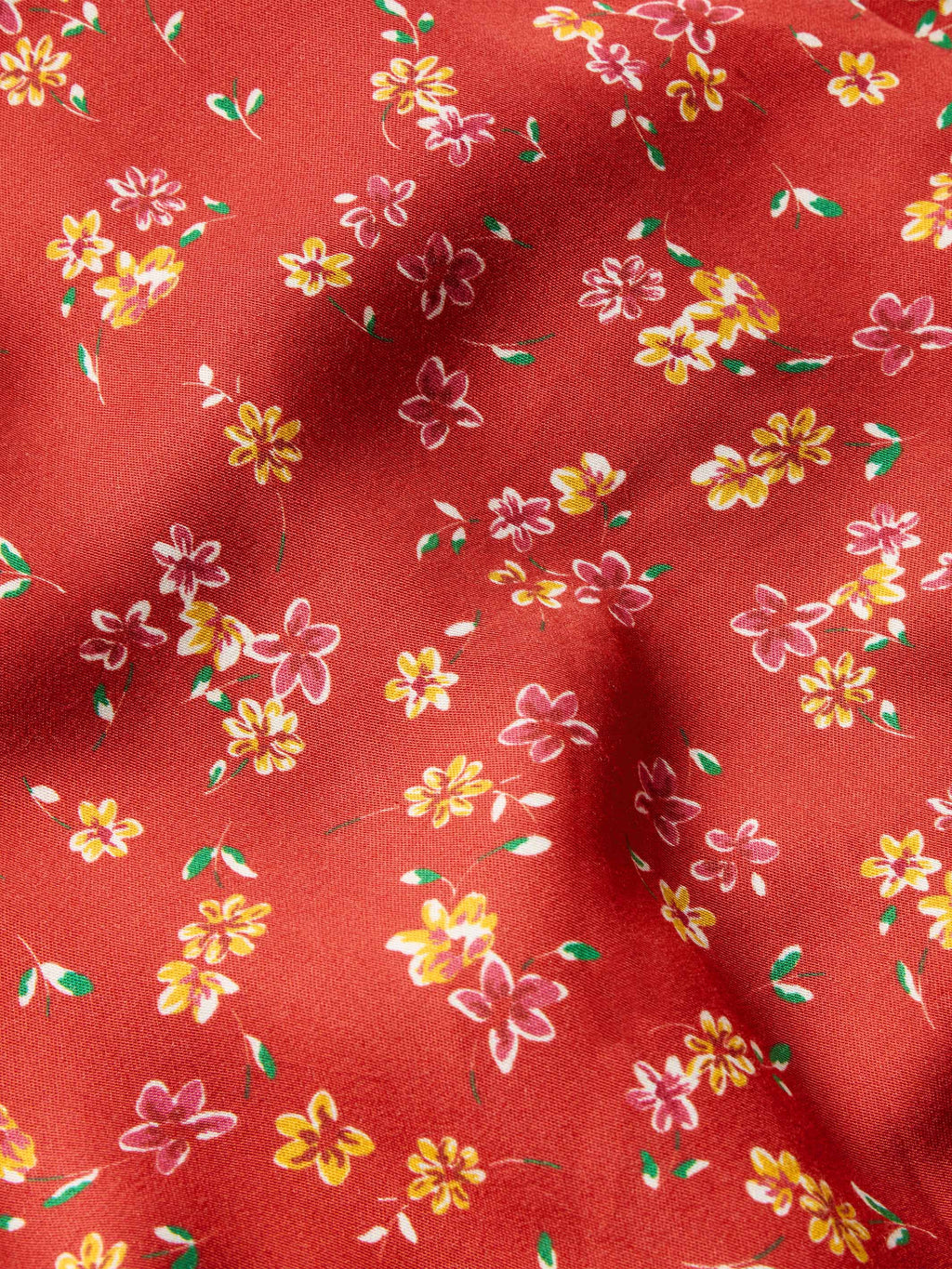 Red floral print fabric close-up with small yellow, pink, and white flowers