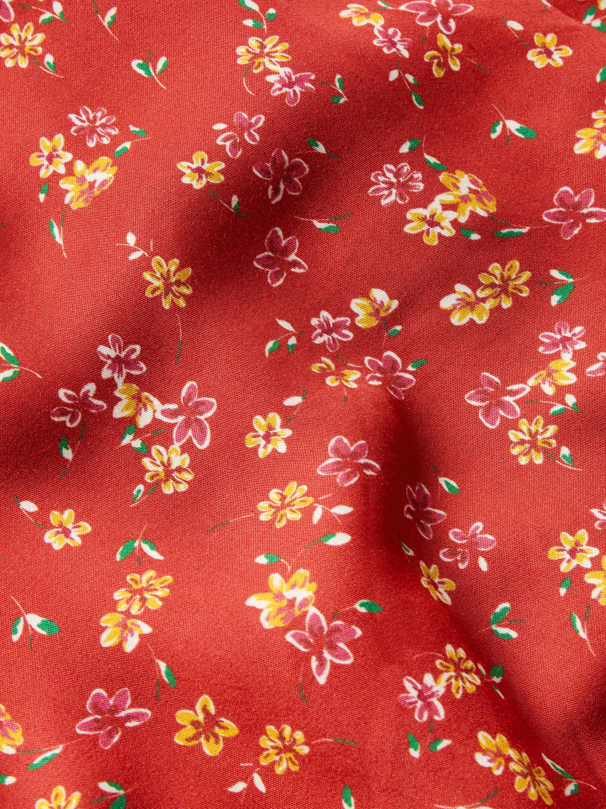 Red floral print fabric close-up with small yellow, pink, and white flowers