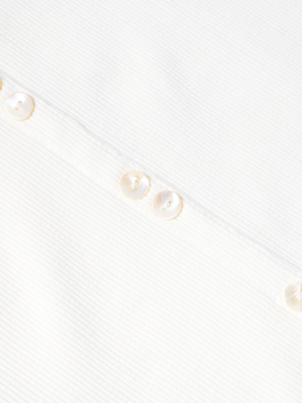 Bone sleeveless dress fabric detail with vertical texture and small gold buttons