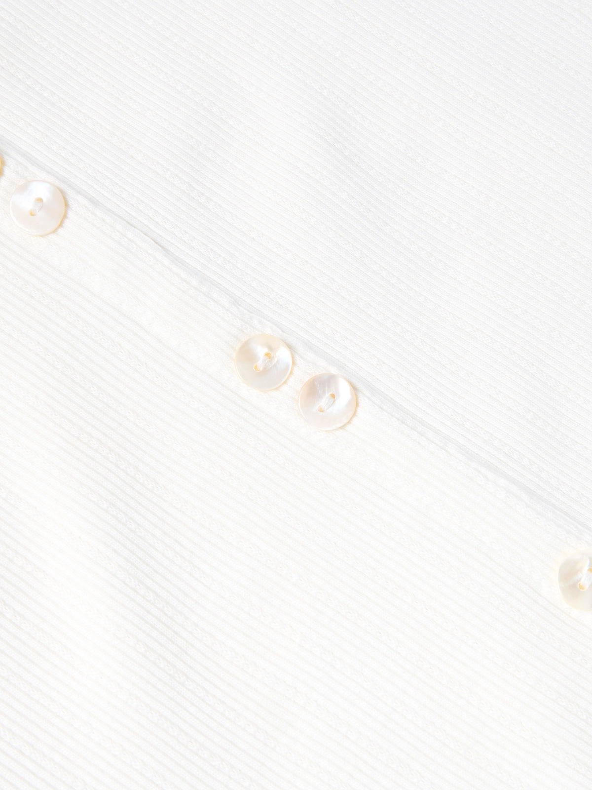 Bone sleeveless dress fabric detail with vertical texture and small gold buttons