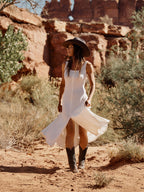 Bone sleeveless dress with scoop neckline and flowing asymmetrical hem