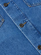 Close-up of indigo denim jacket placket with round metal snaps and tan stitching