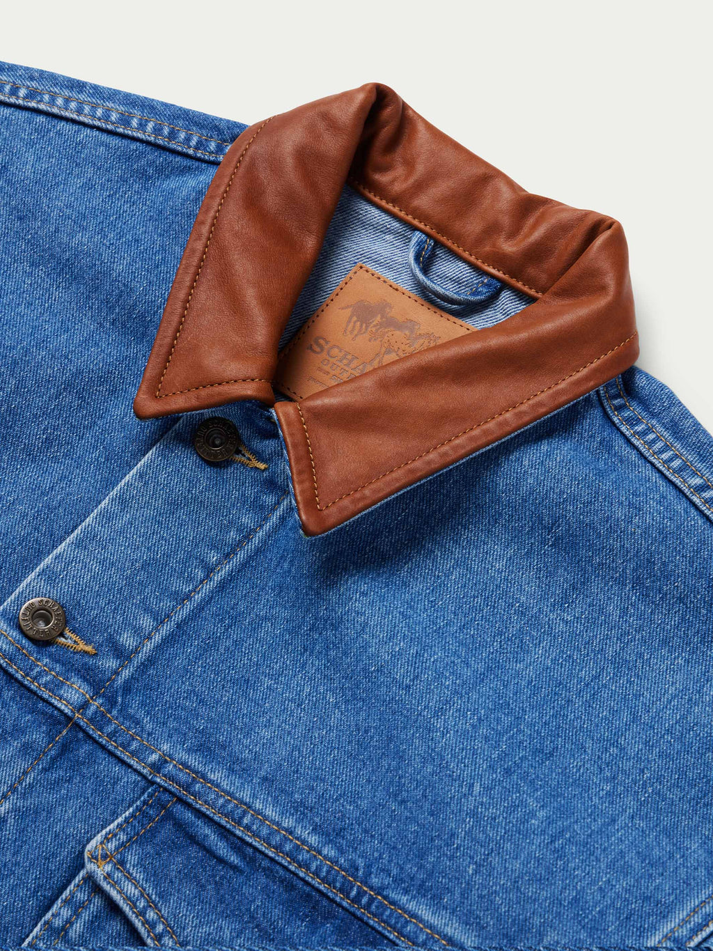 Indigo denim jacket with brown leather-look yoke label and buttoned pocket flap