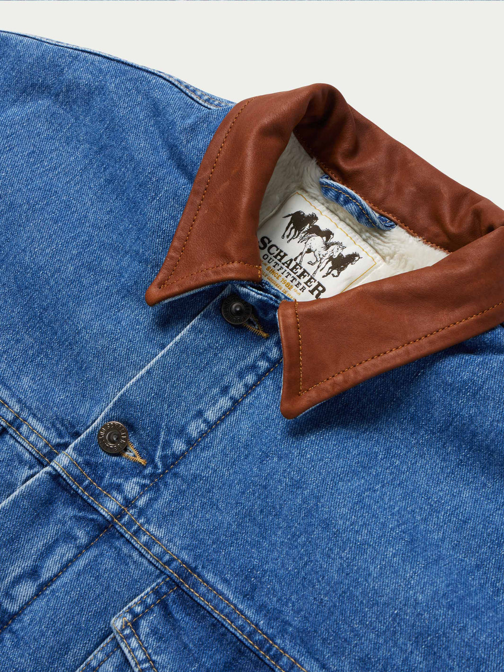 Denim jacket with brown buttoned collar and visible fleece lining at neckline