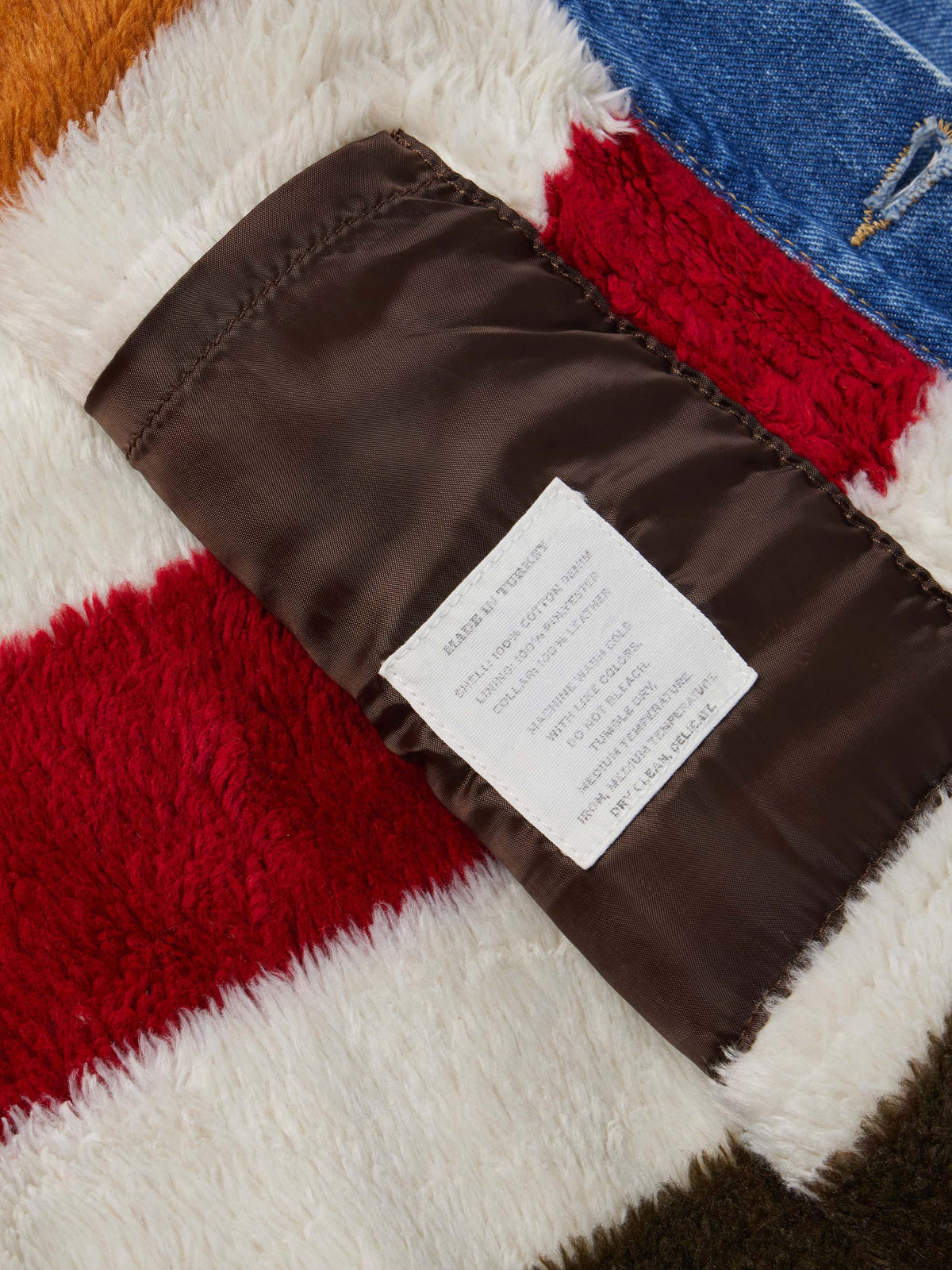 Striped fleece lining inside denim jacket with brown fabric binding and label