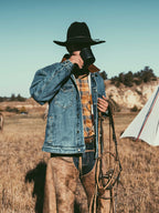 Denim jacket worn by person outdoors over plaid shirt; brown fleece collar visible